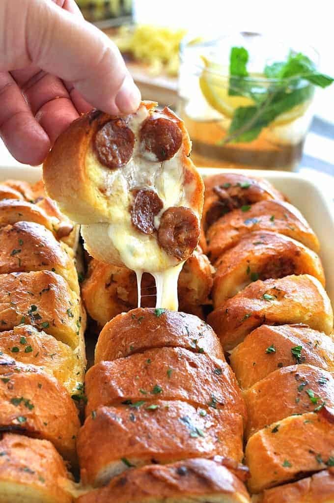 Pulling a piece of Pulling a piece of Pull Apart Pizza Bread out, with cheese strings