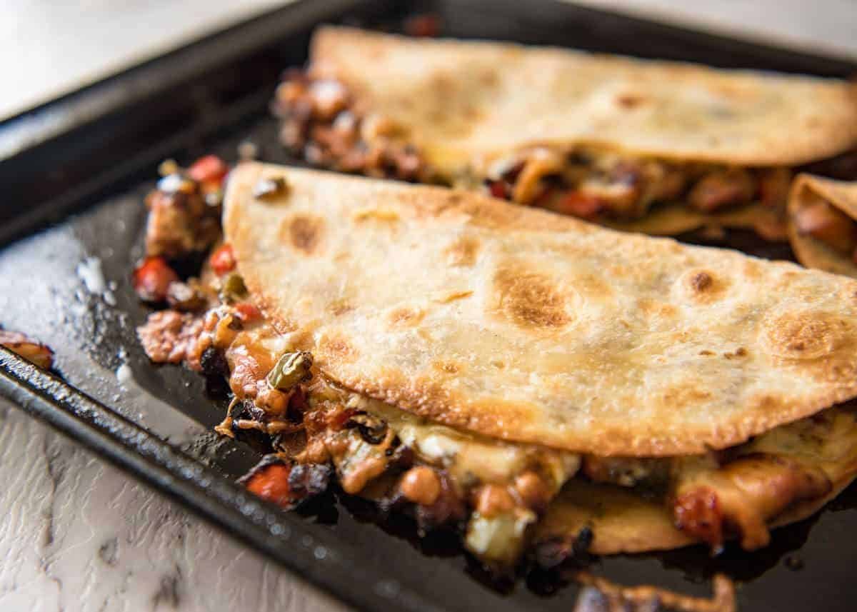 Crispy Oven Baked Chicken Quesadillas - This is how to make multiple Quesadillas at the same time! Crispy on the outside, stuffed with Mexican seasoned chicken and capsicum / bell peppers (and cheese of course!) www.recipetineats.com