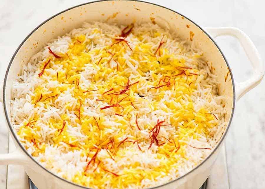 Preparation of Chicken Biryani in a white Chasseur cast iron pot, fresh off the stove